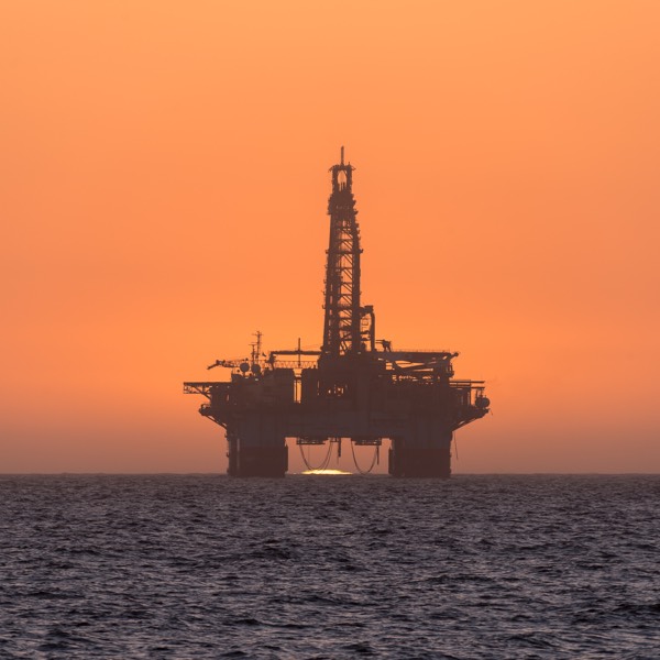 sun setting behind oil drilling platform