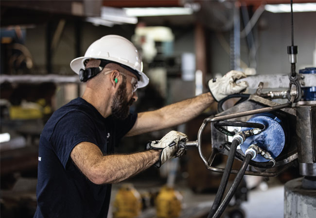 A worker using TorqLite industrial spreader tools for maintenance.