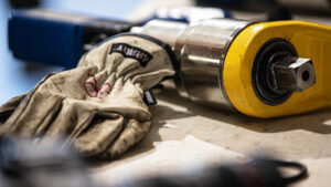 A glove next to an electric high-speed torque multiplier for industrial use, from TorqLite.